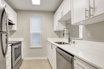 a kitchen with white cabinets and white counter tops and stainless steel appliances at 2000 Lake Washington Apartments, Renton, Washington